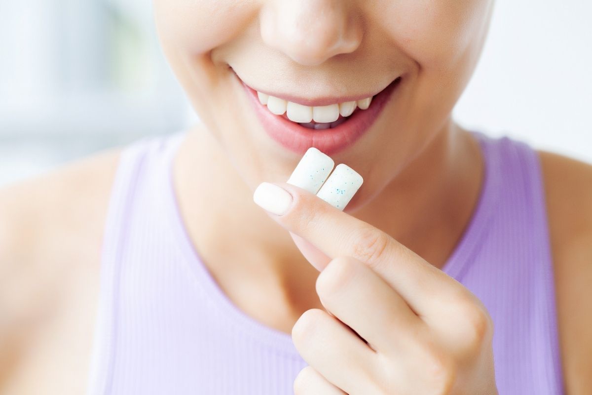 Women with chewing gum in hand showing healthy smile
