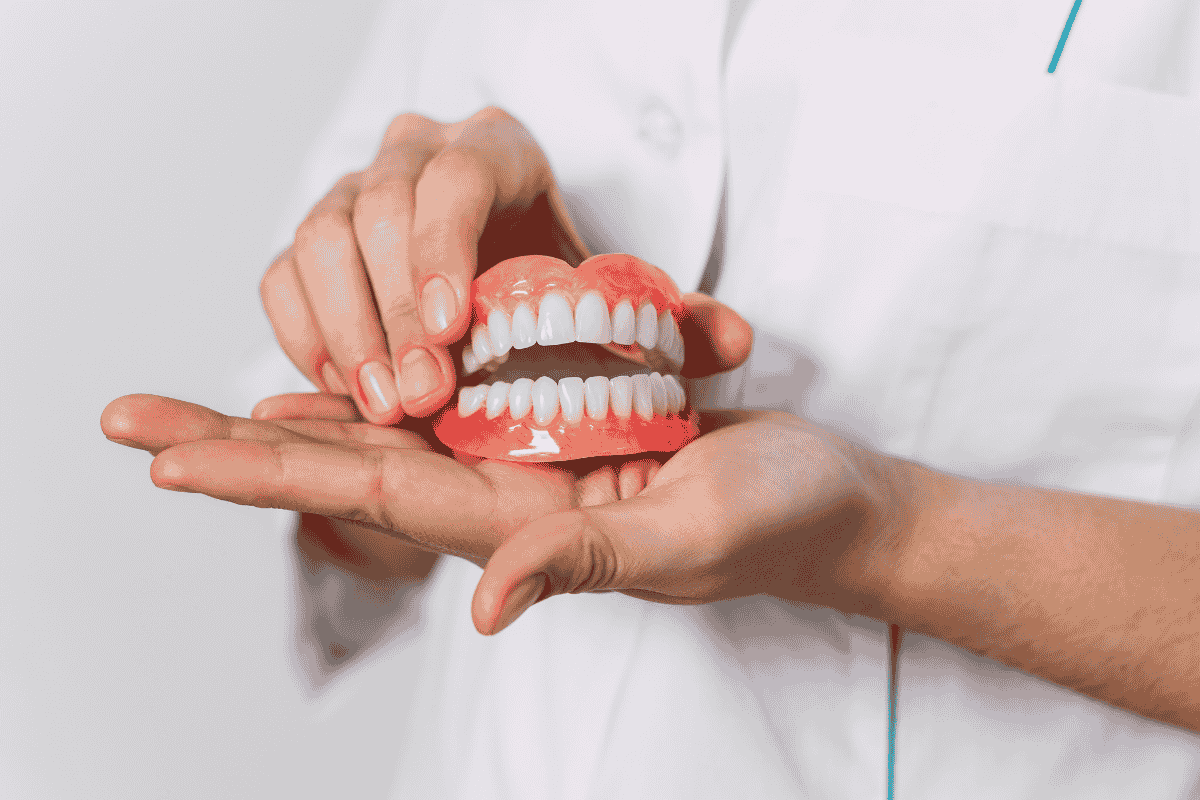 person holding model of full dentures