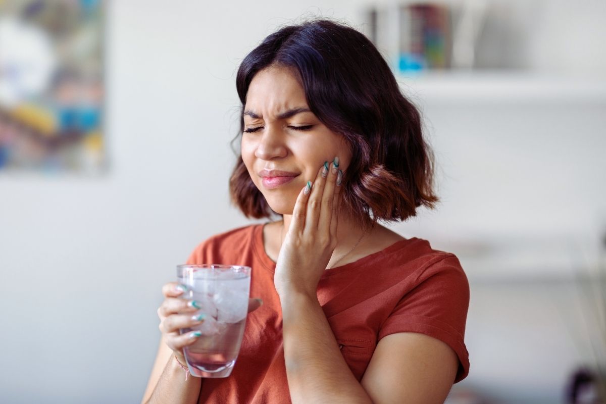 Women in tooth pain holding a glass of ice water