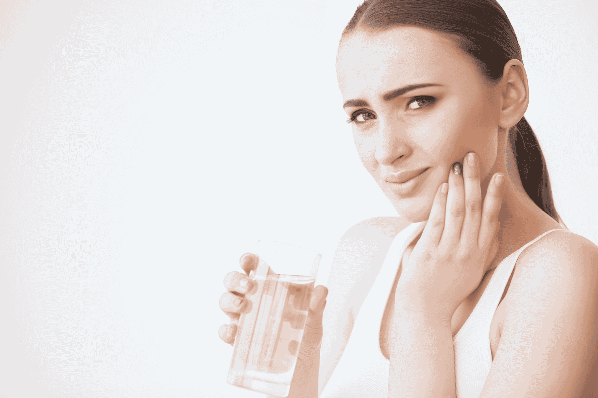 Person with glass of water showing tooth sensitivity