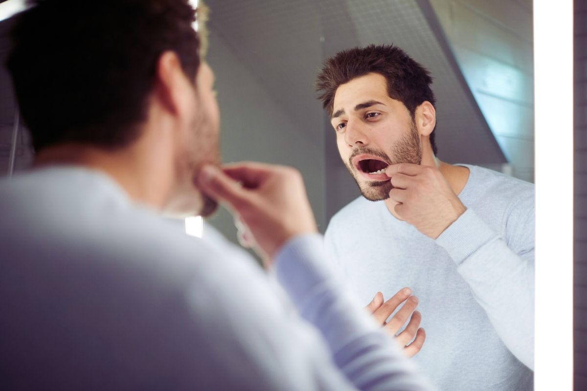 man checking his teeth on mirror looking for chalky teeth