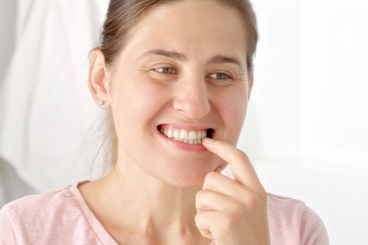 women checking her teeth and gums understanding the causes of bleeding gums
