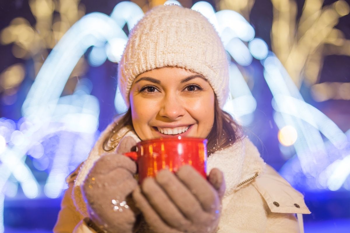 women with a hot drink enjoying winter with a bright smile