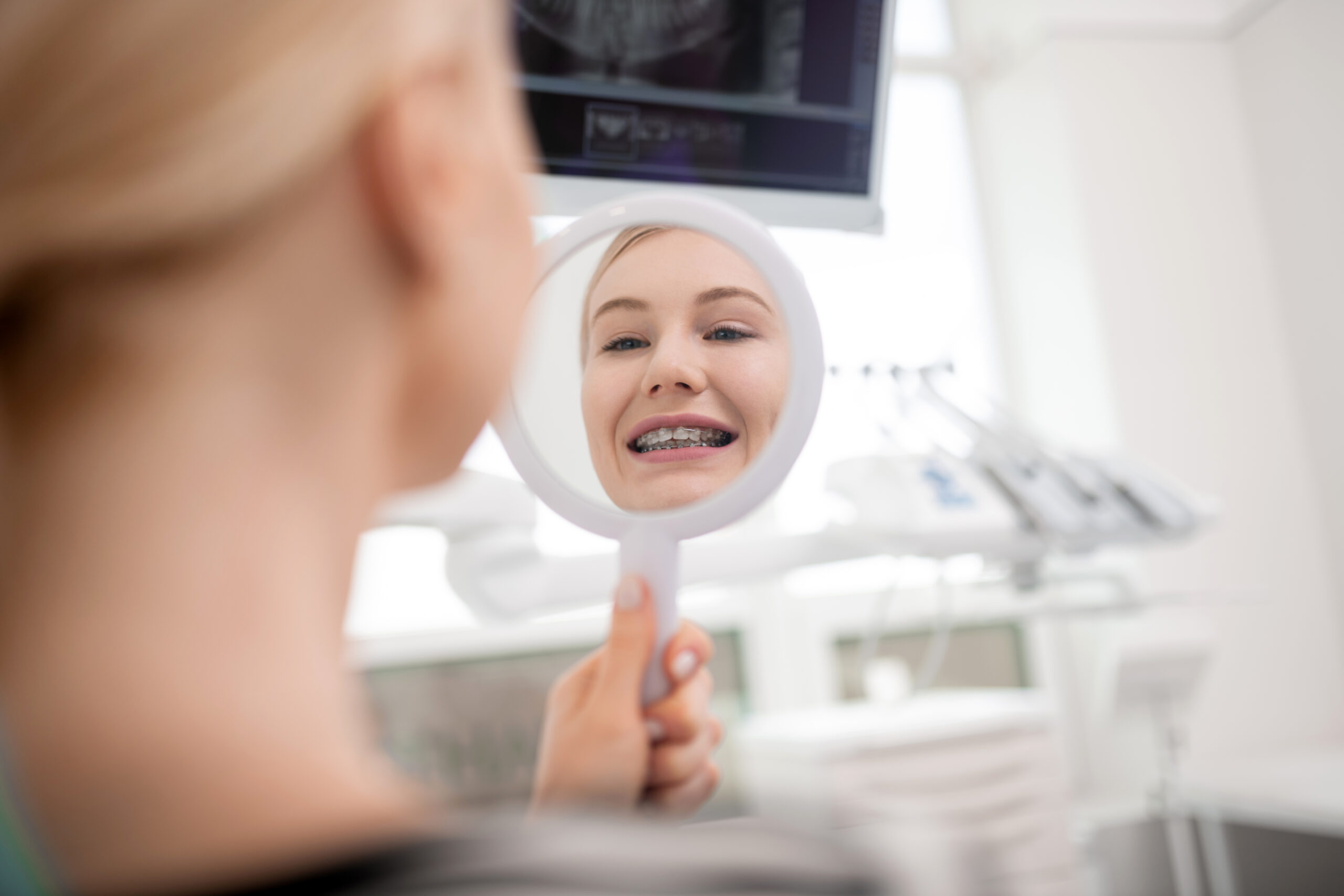 Patient checking her braces in a mirror during an orthodontic visit